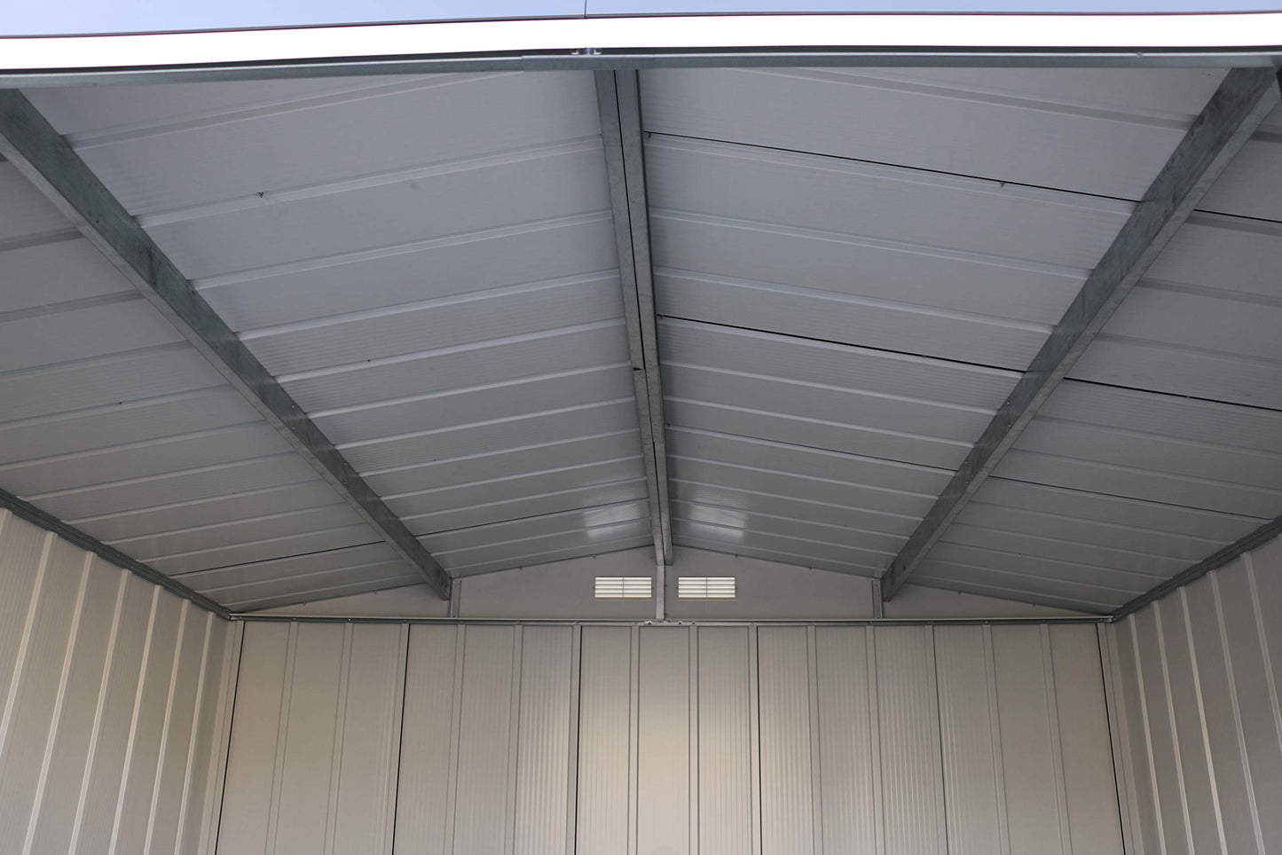 Wide interior view of the shed ceiling with central steel support, ribbed panels and gable vents