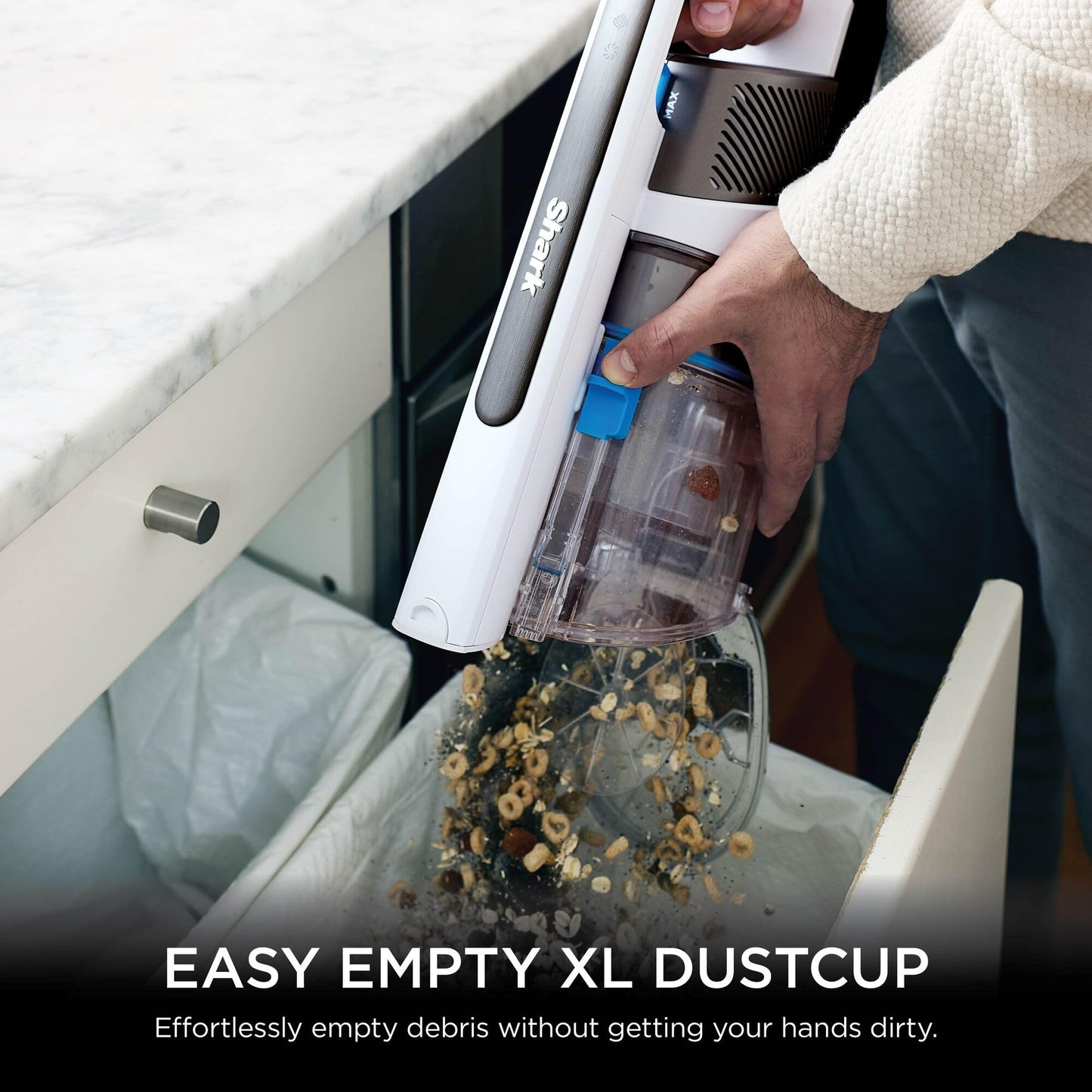Hand removing the XL dustcup and emptying cereal and debris into a bin to demonstrate the easy-empty feature.