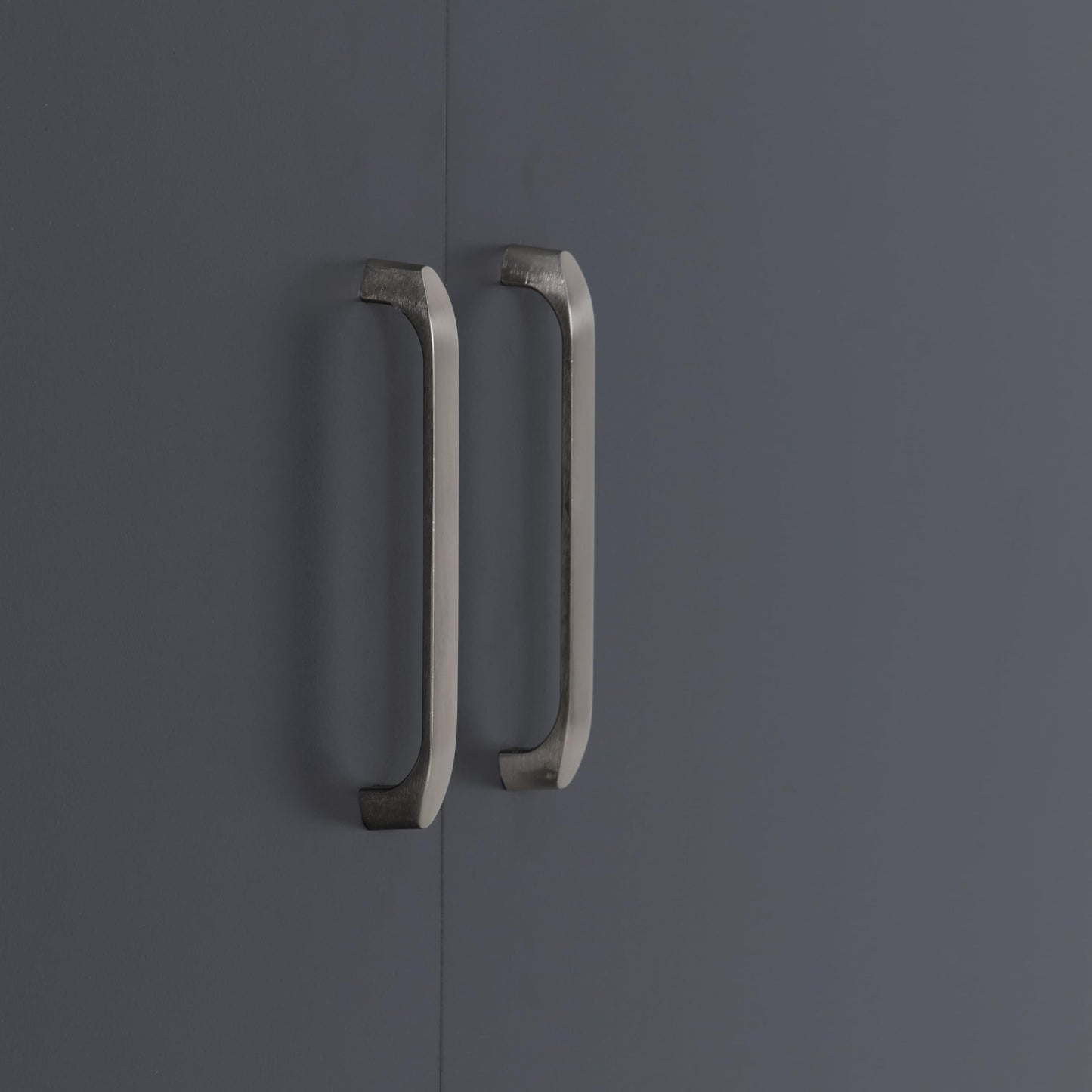 Close-up of two brushed metal vertical handles mounted on dark grey wardrobe doors