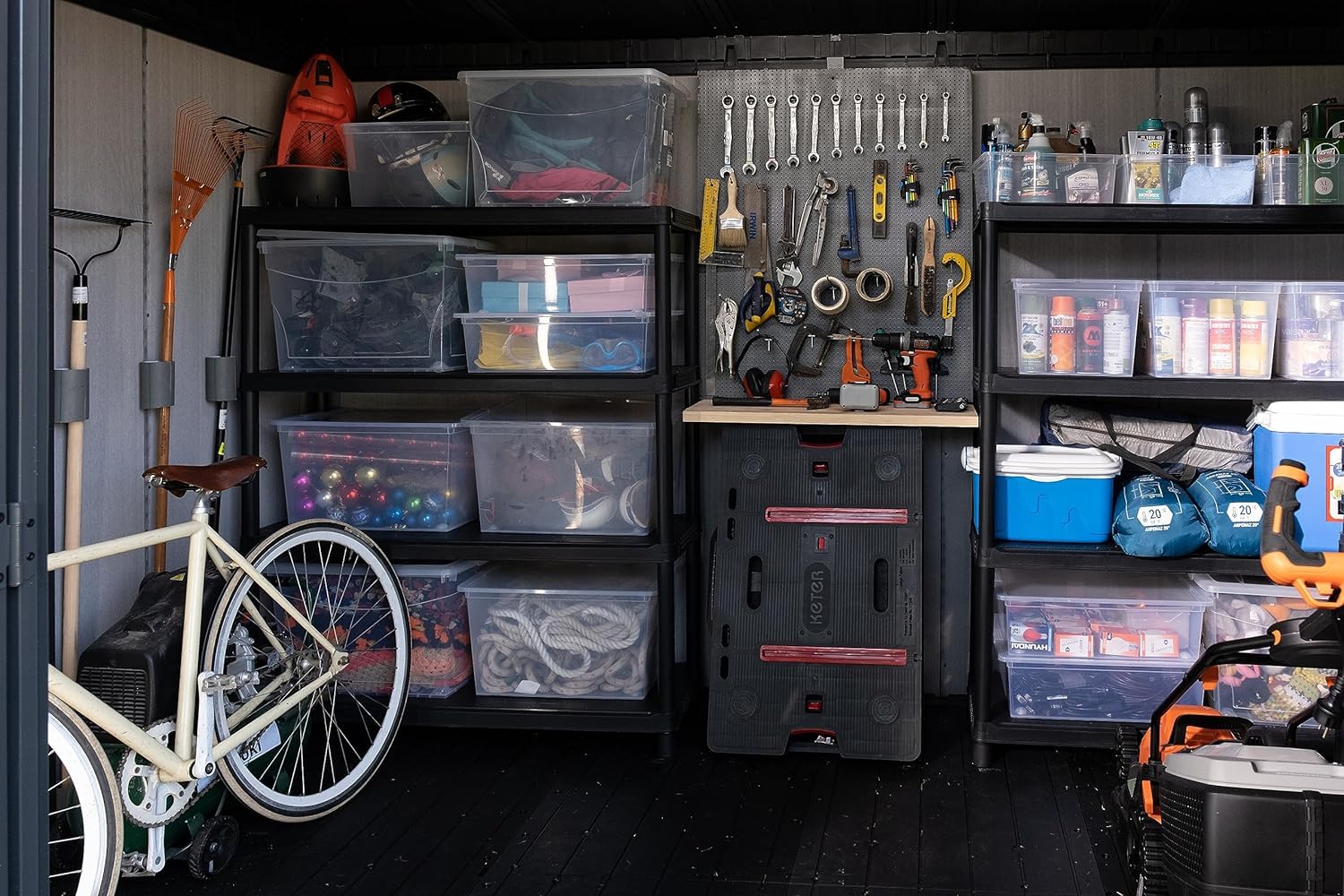 Interior view showing organised shelving, clear storage boxes, pegboard of tools and a bicycle