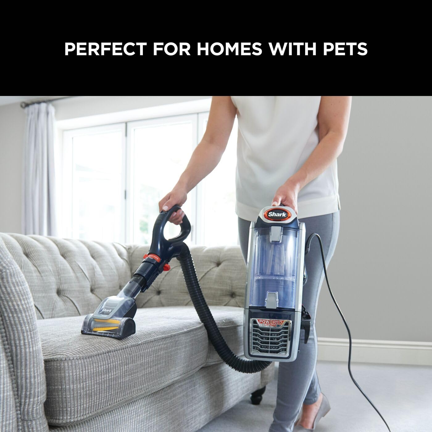 Person using the Lift-Away portable unit and motorised pet tool to clean a sofa upholstery.