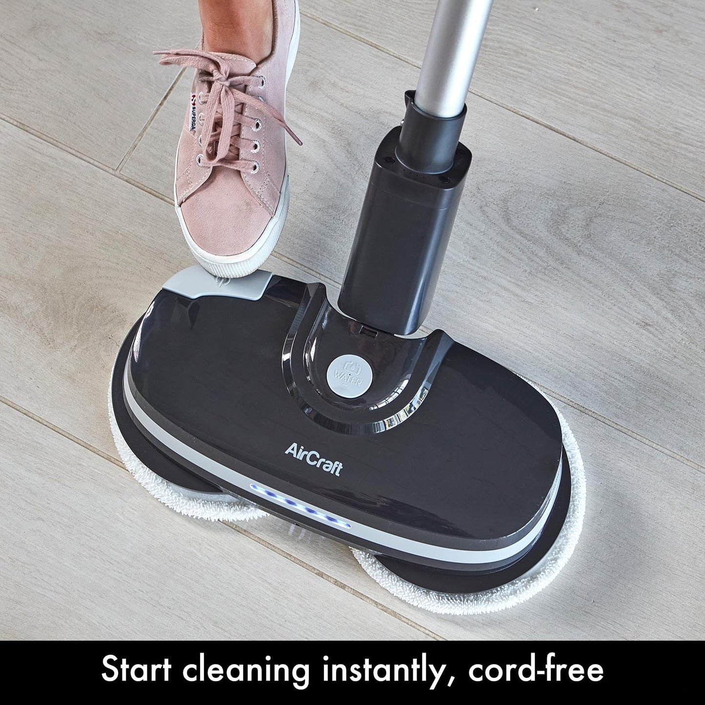 Foot pressing the PowerGlide's top release/power button on the base while standing on a tiled floor