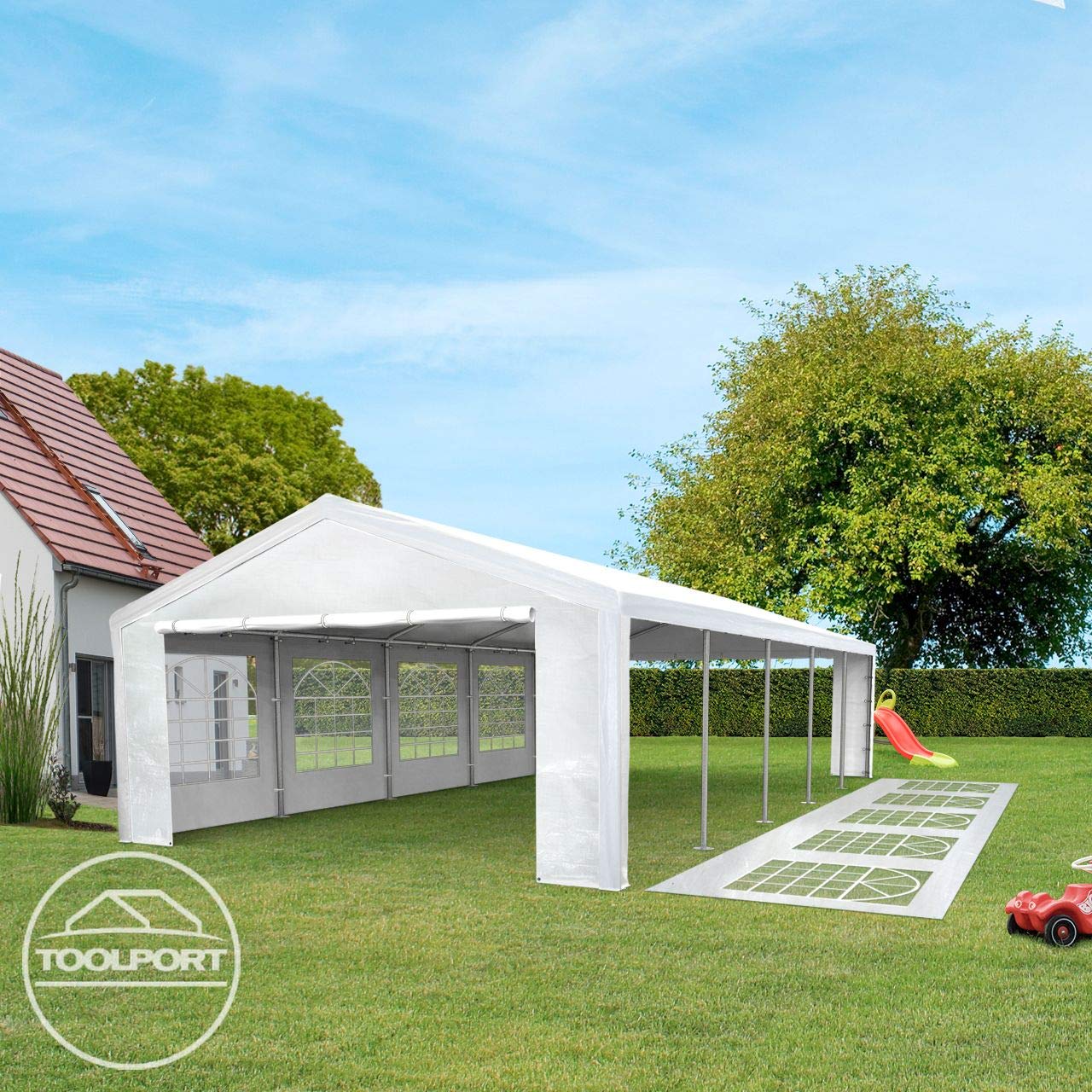 Angled view of marquee with an open side, spare window panels laid on the lawn and children's toys at the edge