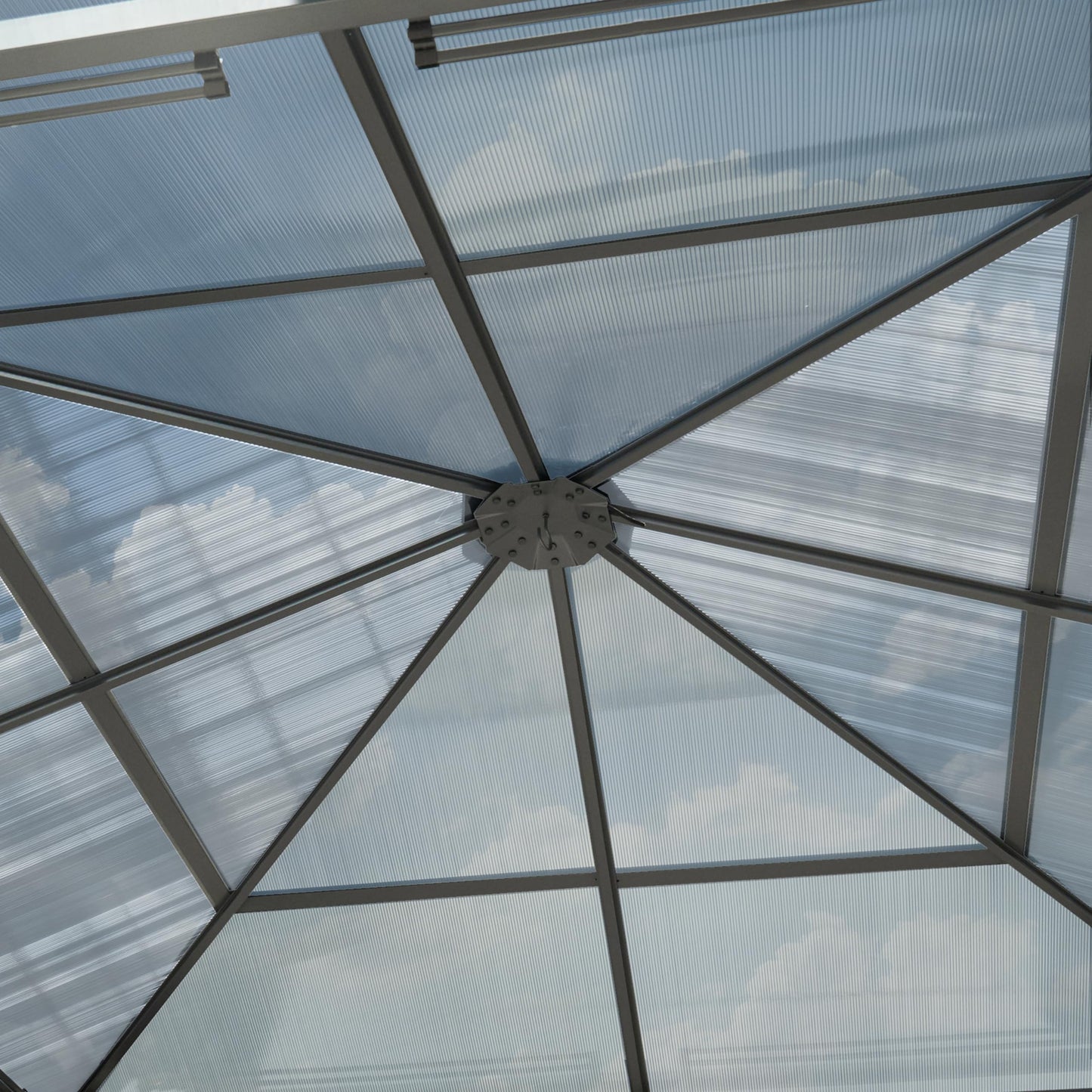 Interior upward view of the gazebo showing the central roof hub and radial aluminium supports beneath the panels.