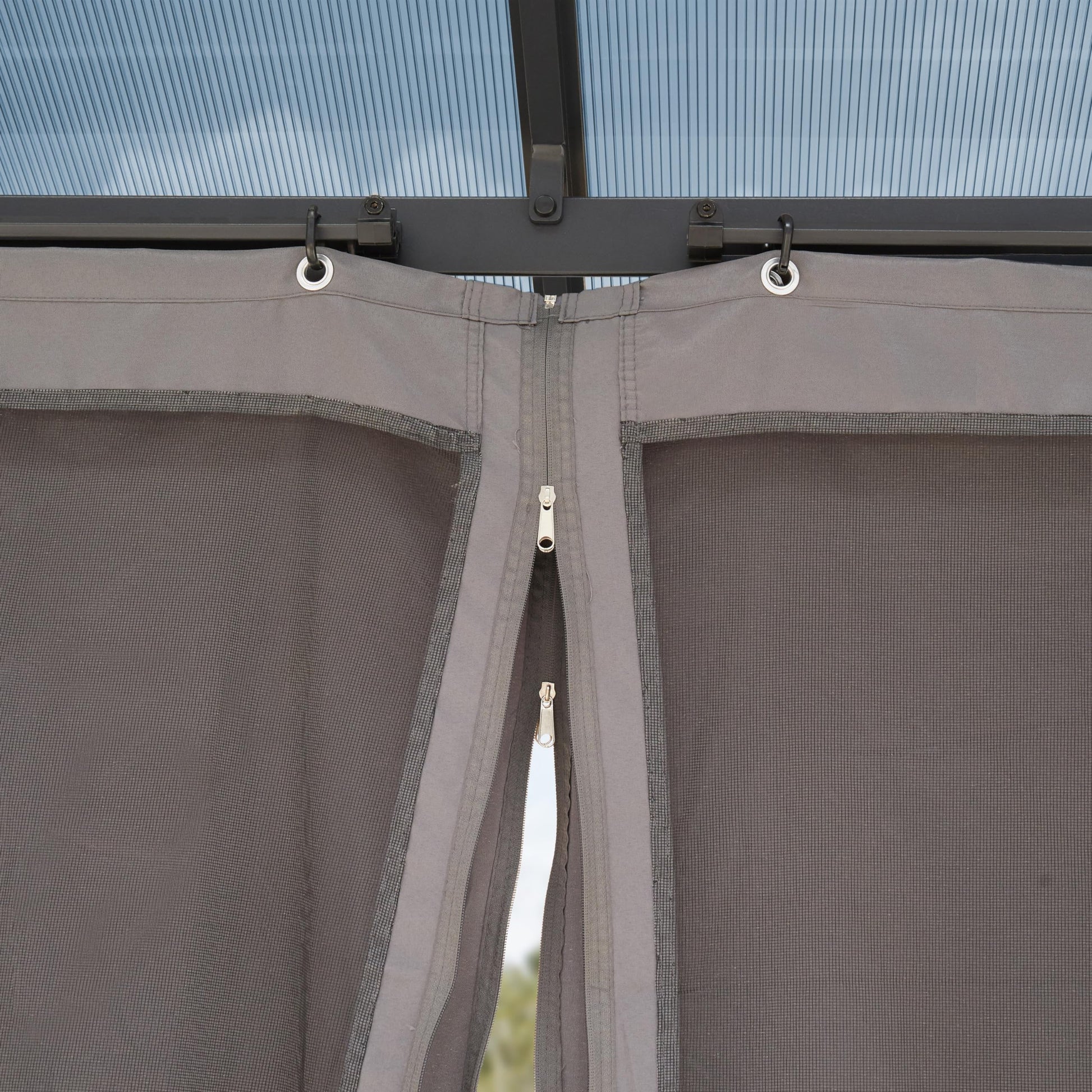 Top of a side curtain with metal grommets on hooks and a central zipper joining two mesh panels.